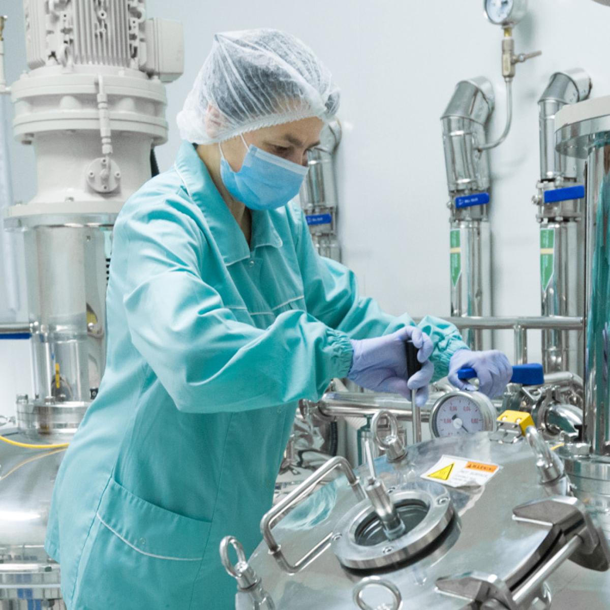 Femme en vêtement de protection jetable dans une usine pharmaceutique